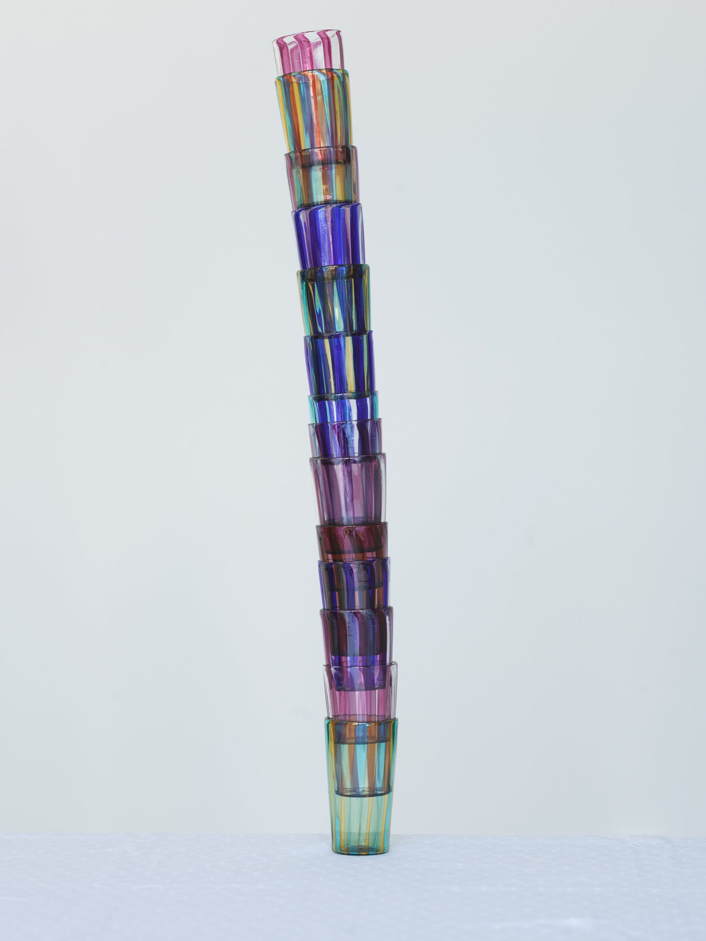 Multiple small striped handmade glasses in vibrant colors made in Murano.