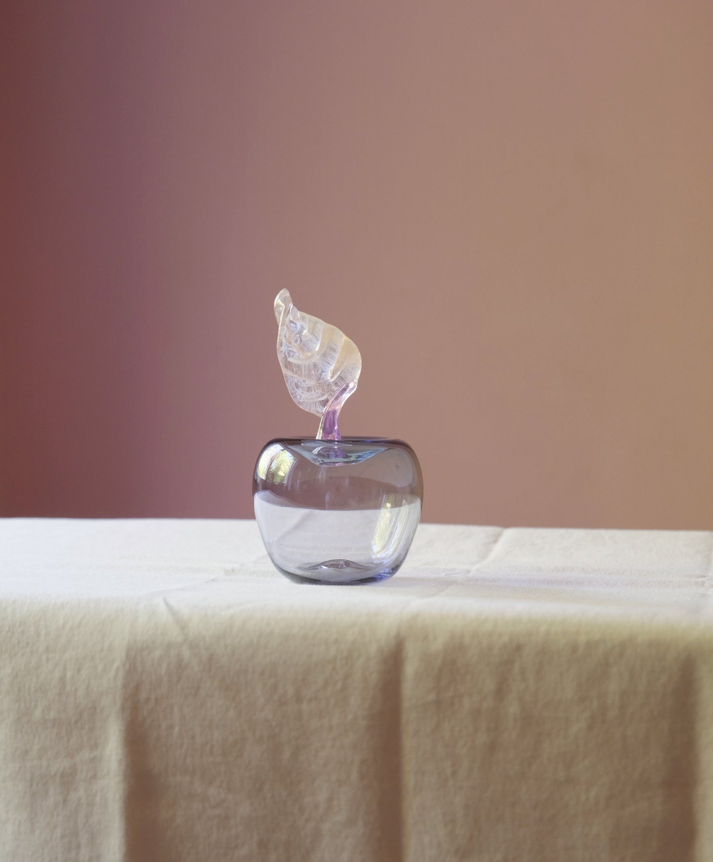 Mouth blown glass paperweight shaped as an apple placed on a table.