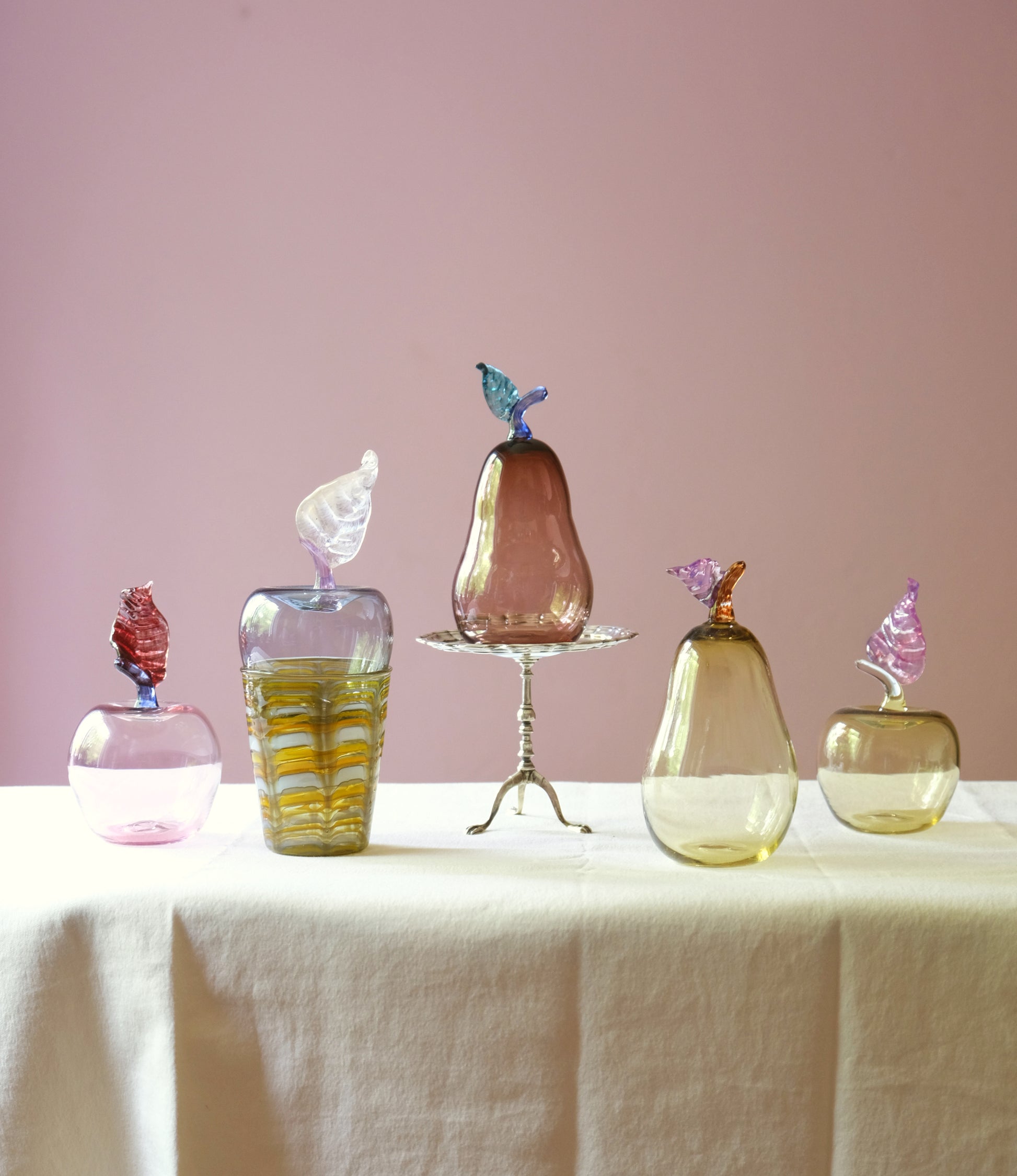 Mouth blown glass paperweights shaped as apples and pears placed on a table.