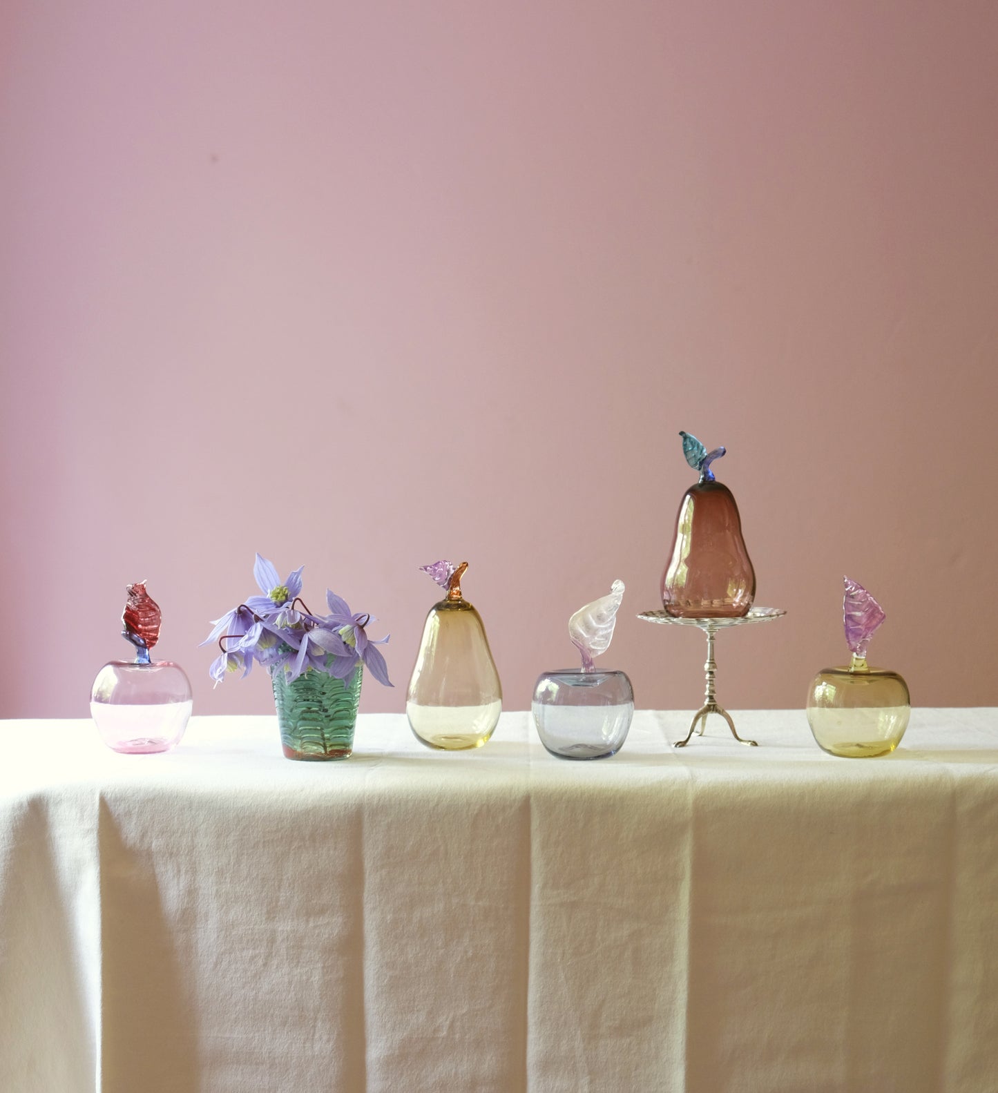 Mouth blown glass paperweights shaped as apples and pears on a table.