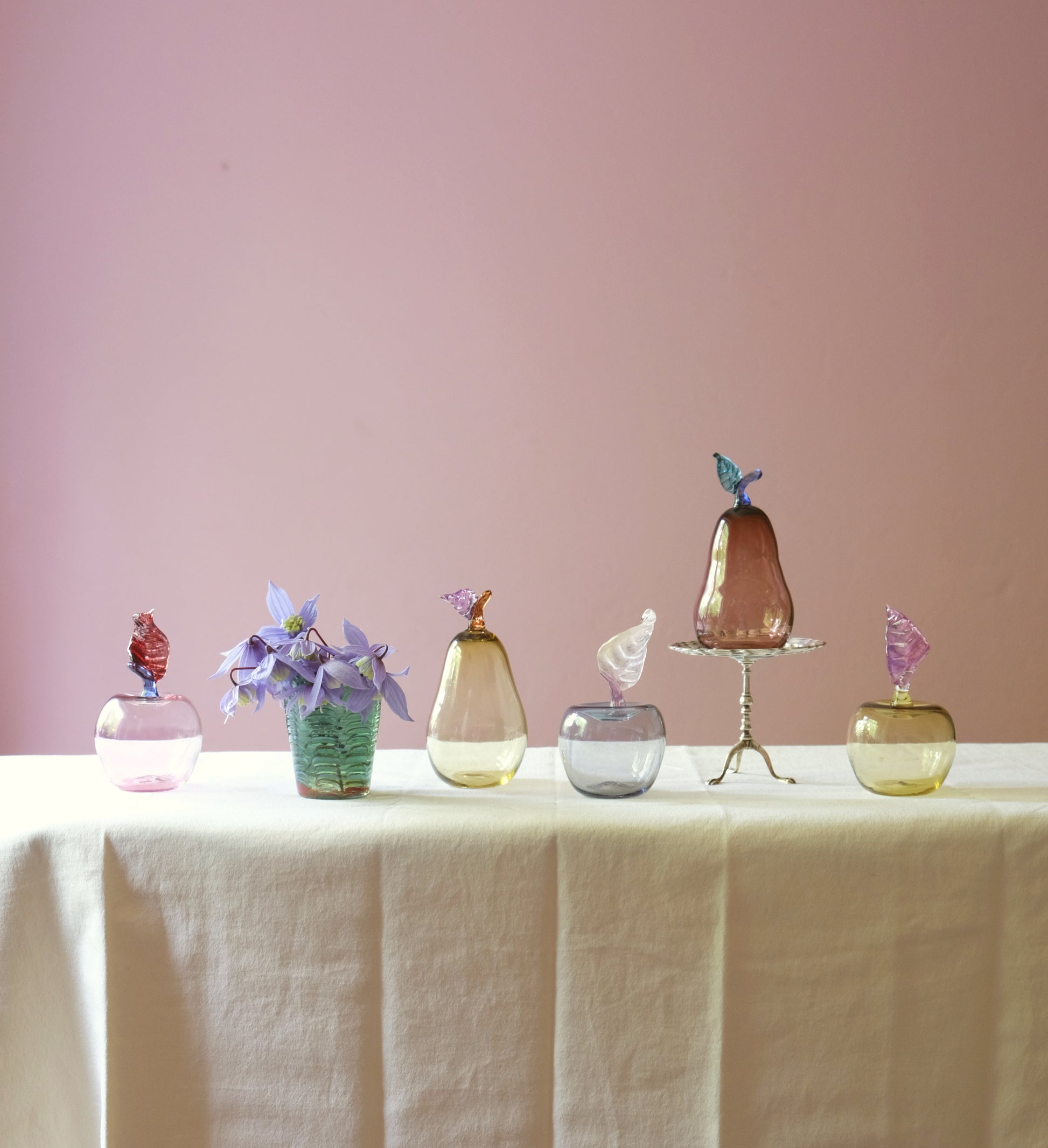 Mouth blown glass paperweights shaped as apples and pears on a table.