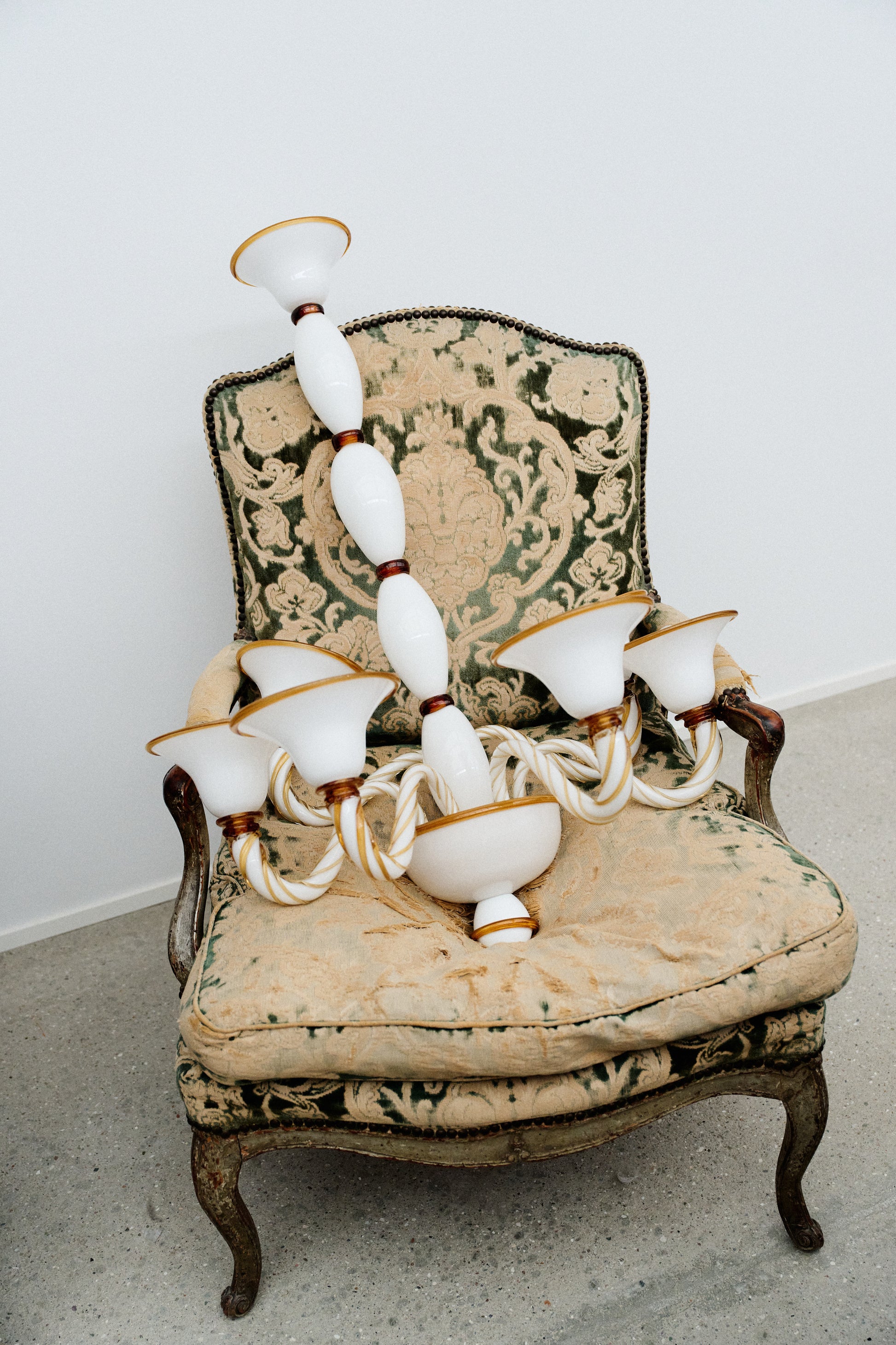 Long Murano glass chandelier in opal and amber laying in chair.