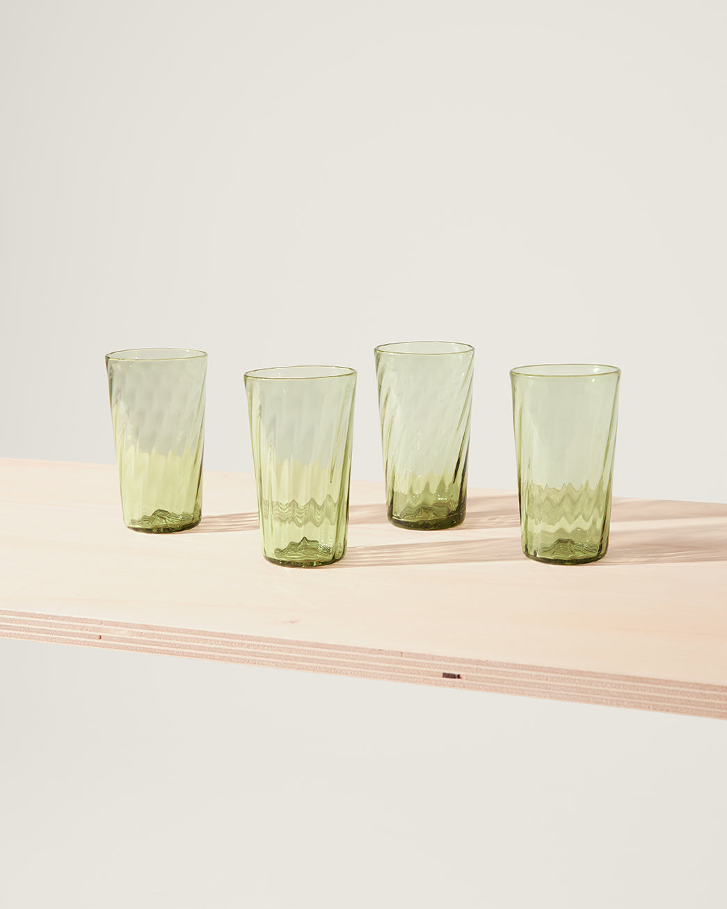Large green Murano glasses with swirl details on a table.