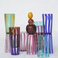 Multiple small striped handmade Murano glasses and fruits in different colors.