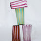 Multiple small striped handmade Murano glass in blue, yellow, brown and pink.