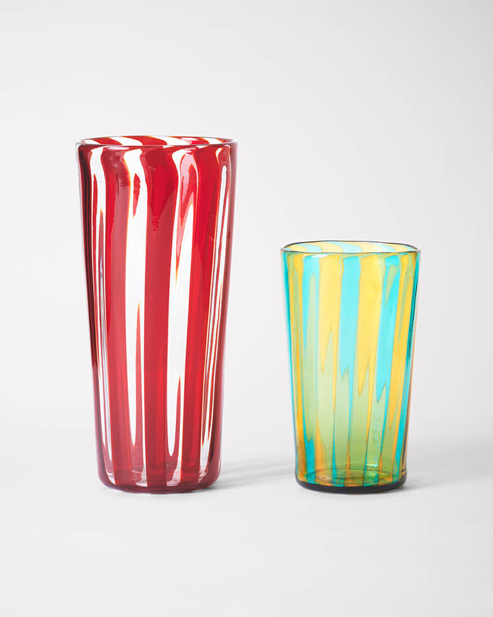 Small and large striped handmade Murano glasses in red, blue and yellow.