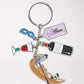 Keychain with colorful enamel charms of a gondola, wine bottle & glass, venetian mask, and "Akua" tag.